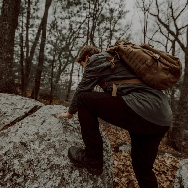 A man in the woods with a tactical backpack.